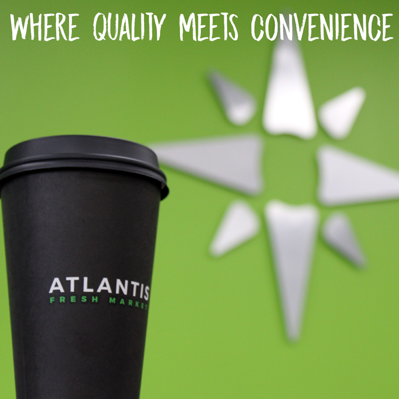 The coffee cup with the Atlantis Fresh Market logo in front of the Atlantis Fresh Market Star Logo has the words 'Where quality meets convenience' written on it.